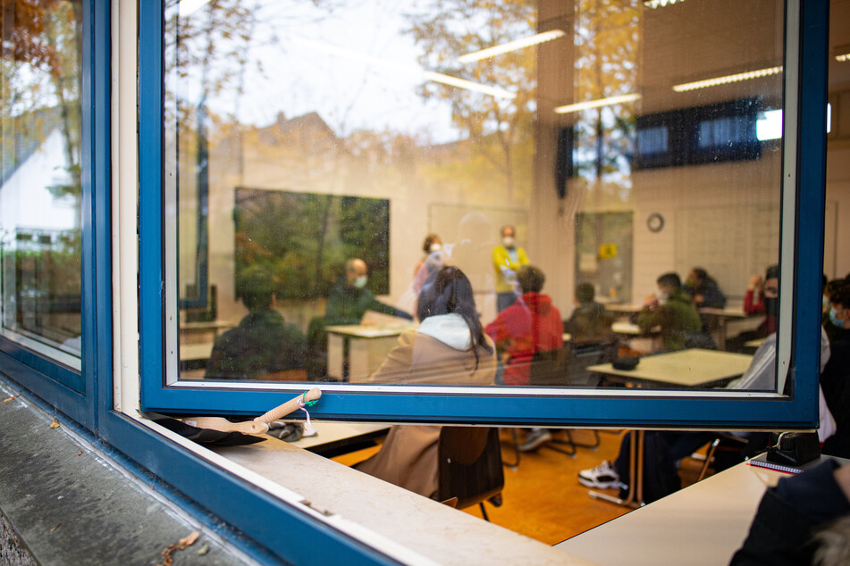 Blick durch das offen stehende Fenster in den Klassenraum einer Schule.
