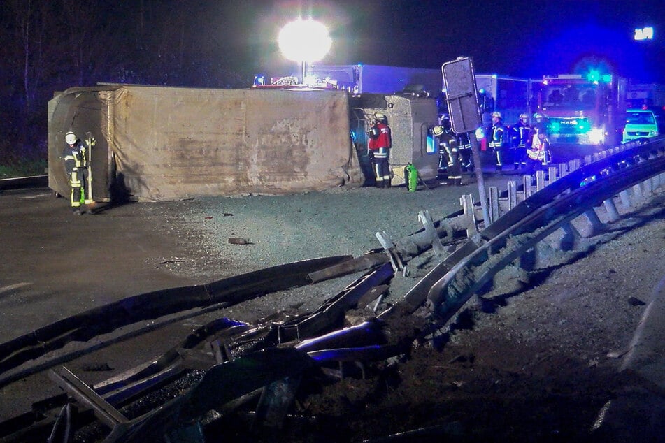 Feuerwehrleute stehen neben dem umgekippten Lastwagen auf der A1.
