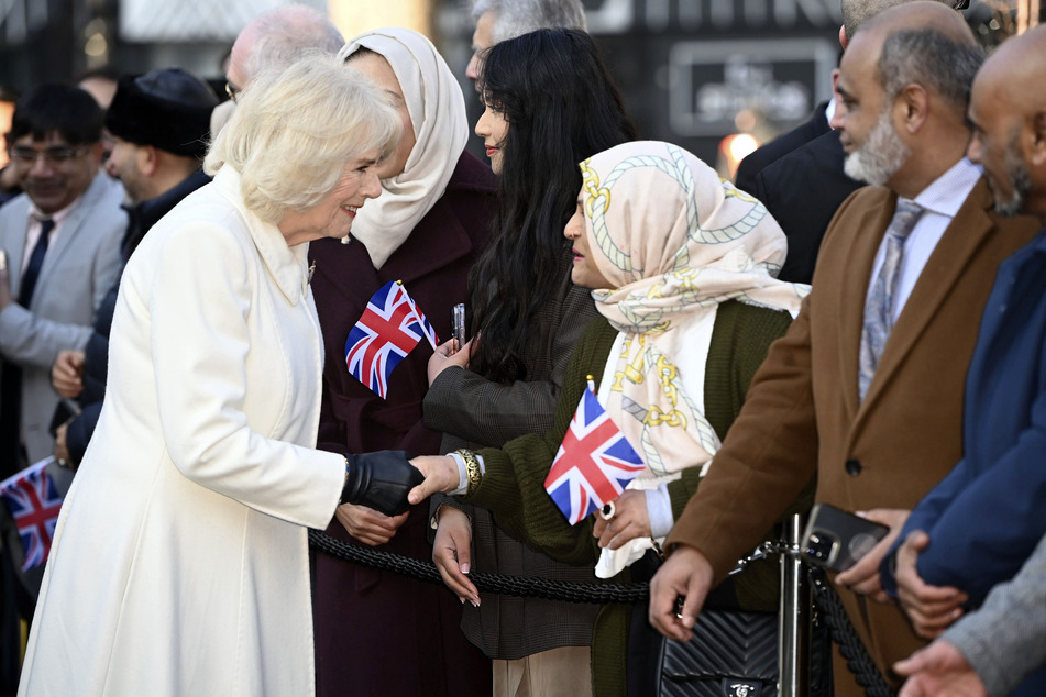 Königsgemahlin Camilla gibt einer Frau die Hand, während sie und der britische König die Brick Lane im Osten Londons besuchen, um sich mit Wohltätigkeitsorganisationen und Unternehmen zu treffen. Die Queen Consort genießt solche Termine sichtlich.