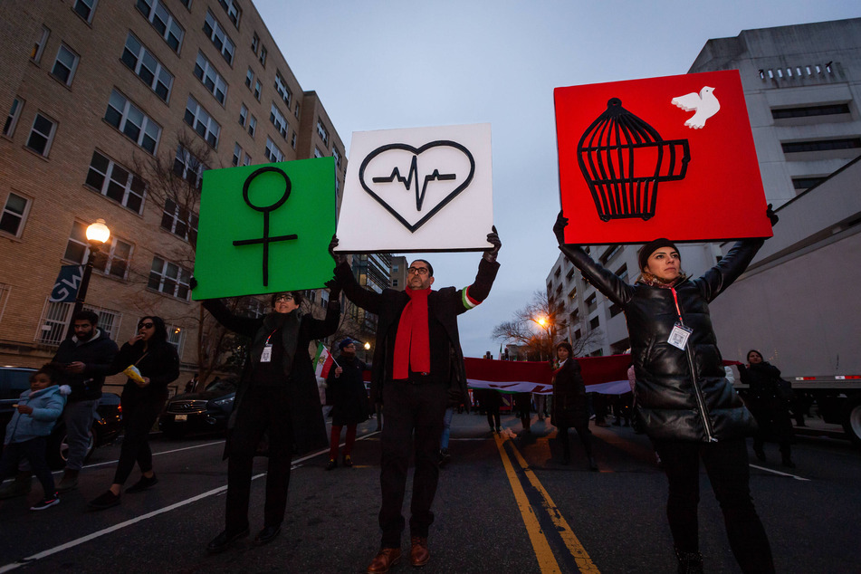 People carry Wman, Life, Freedom signs at a march in support of protesters in Iran, on January 8, 2023, in Washington DC.