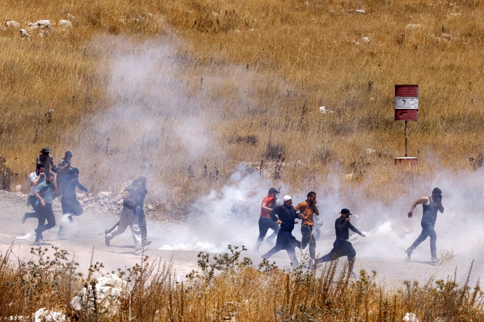 Members of Syria's Druze community walk through tear gas fumes released by Israeli forces to disperse them, as they gather along the dividing line to attempt to cross the barbed-wire fence with the Israeli-annexed Golan Heights near Majdal Shams on Wednesday.
