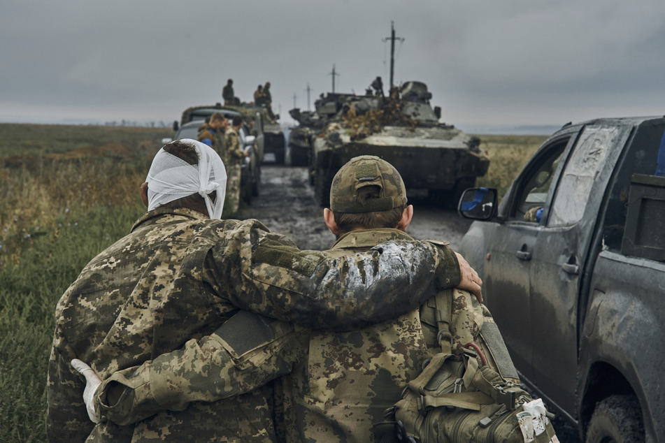 Ein ukrainischer Soldat hilft einem verwundeten Kameraden auf der Straße in dem befreiten Gebiet in der Region Charkiw. Die ukrainischen Truppen haben am Montag weite Teile des russischen Territoriums zurückerobert und sind teilweise bis an die nordöstliche Grenze vorgedrungen.