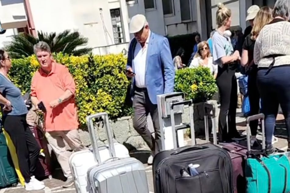 Die Reisende filmte eine Gruppe von Menschen, die mit ihren Koffern vor dem überfüllten Hotel stehen.