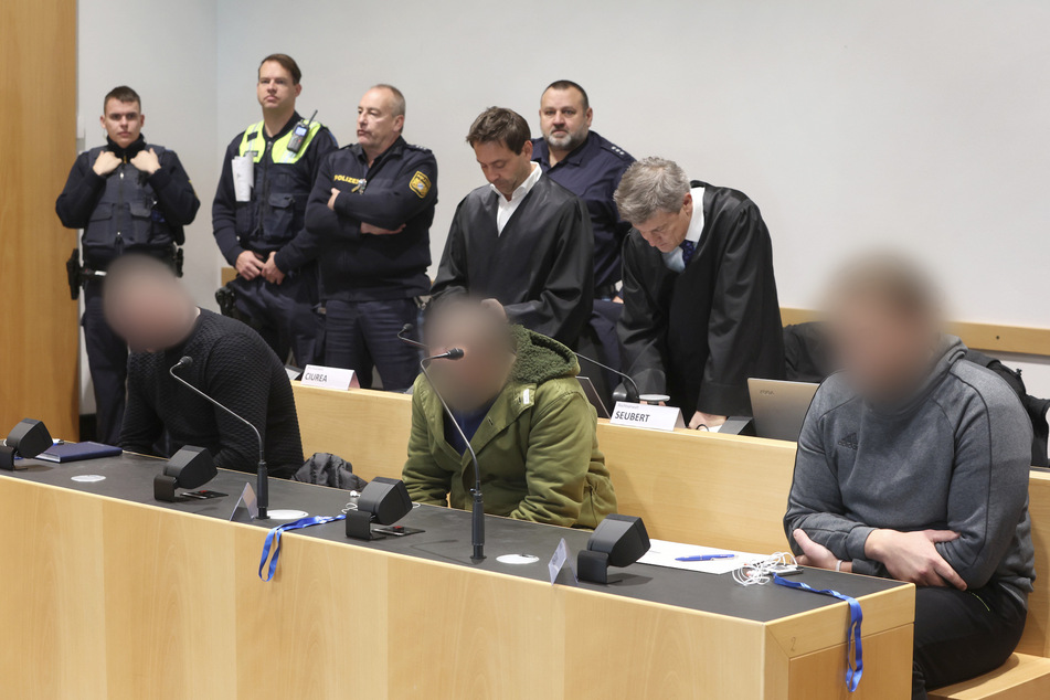 Die drei Männer sitzen in der Anklagebank des Landgerichtes Augsburg.