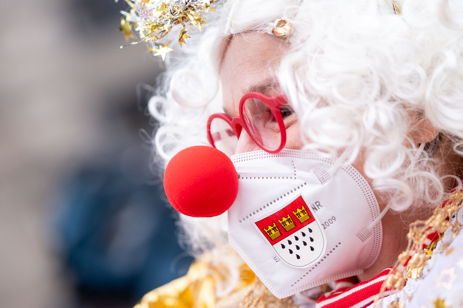 Eine Frau mit Coronaschutzmaske und Verkleidung im Karneval in Köln.