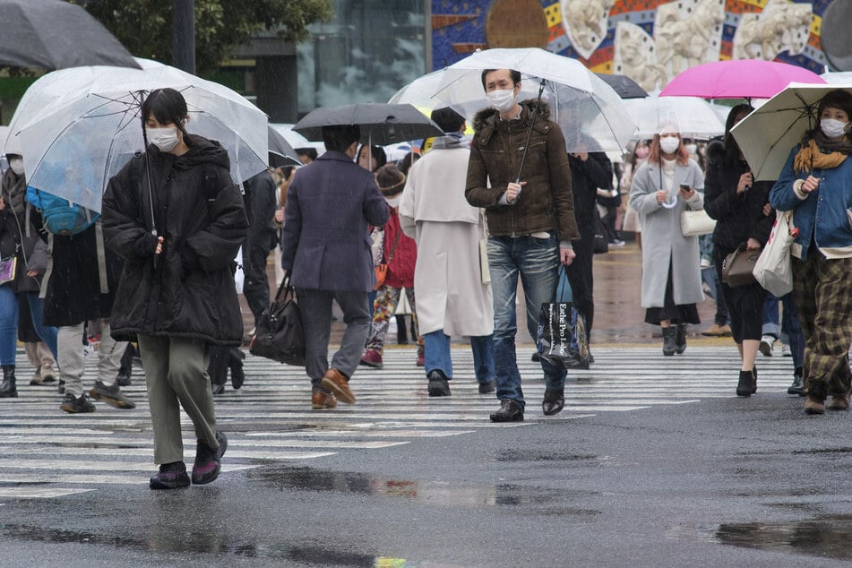Menschen gehen im Februar 2022 inmitten der Coronavirus-Pandemie im verregneten Tokio spazieren.