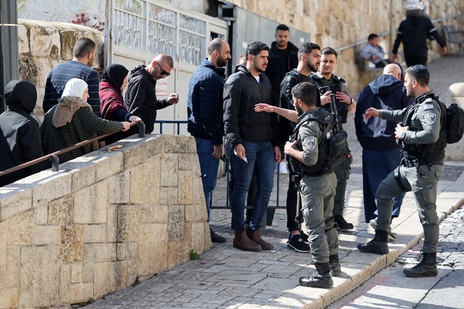 A member of the Israeli security forces checks identity cards as Muslim worshippers wait at a checkpoint to enter the Al-Aqsa Mosque compound before the Friday noon prayer in Jerusalem.