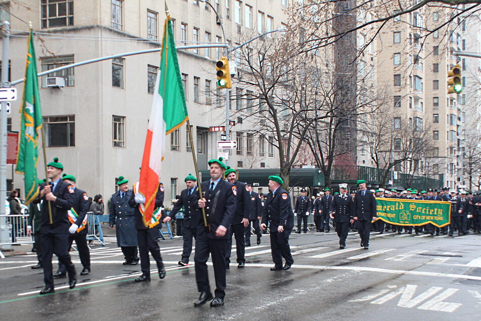 The Emerald Society marches pass 69th Street, alongside Central Park.