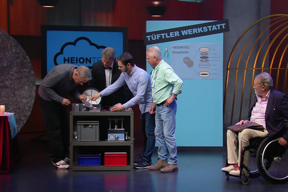V.l.n.r.: Löwe Frank Thelen schaut sich die Erfindung von Dr. Frank Schneider, Waldemar Lewtschenko, Anton Ledwon und Andreas Heine genau an.