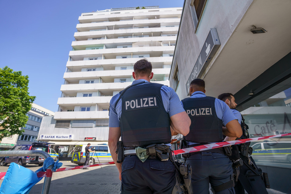 Polizisten stehen vor dem Hochhaus in der Hanauer Innenstadt, in und vor dem sich das Familiendrama mit zwei toten Geschwistern ereignet hat.