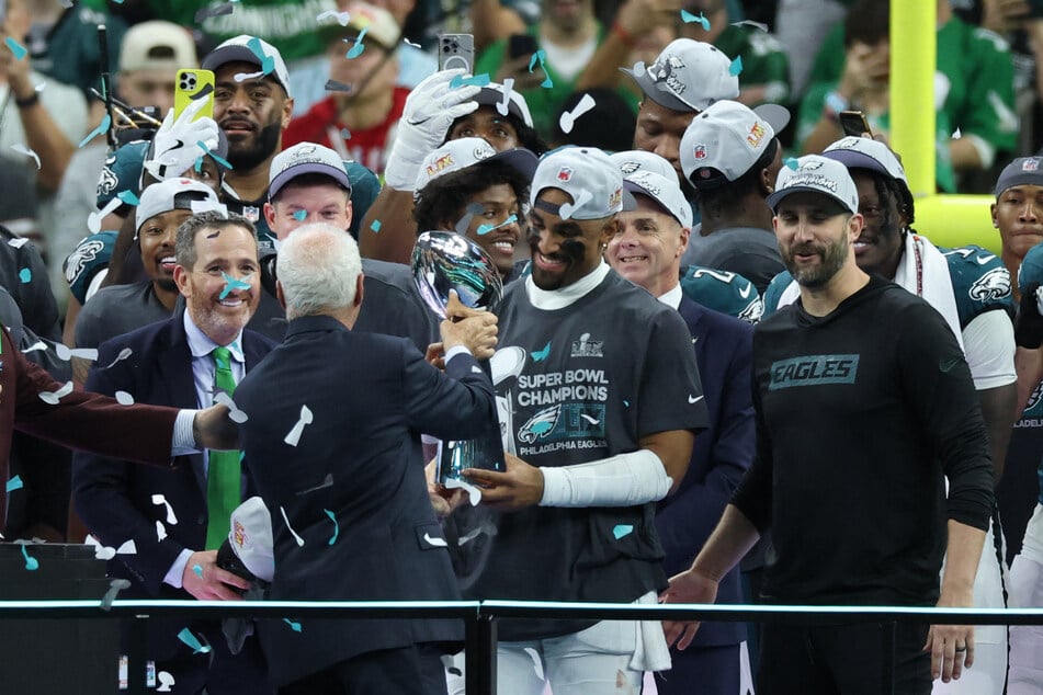 Philadelphia Eagles owner Jeffrey Lurie passes the Vince Lombardi Trophy to Philadelphia Eagles quarterback Jalen Hurts after defeating the Kansas City Chiefs in Super Bowl LIX at Ceasars Superdome.