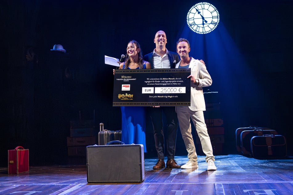 En el marco de las celebraciones, Tom Felton entregó junto con Marcel Neitzel, director del Teatro en el Großmarkt (m.), un cheque de donación de 25.000 euros a Fabienne Ackermann de la "Aktion Mensch".