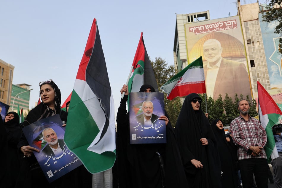 People hold Palestinian flags as they attend a rally following the killing of Hamas' political leader Ismail Haniyeh, in Tehran, Iran.