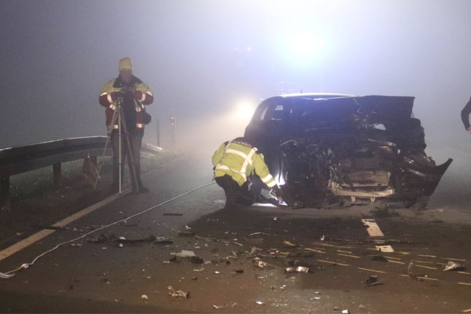 Beamte am Wrack des völlig demolierten 1er BMW.