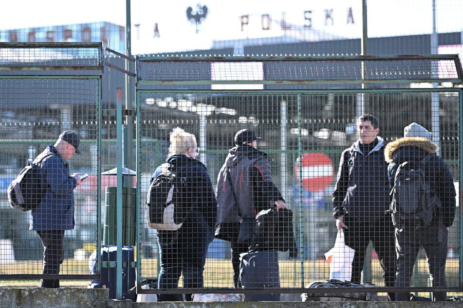 Menschen stehen mit ihrem Gepäck am polnisch-ukrainischen Grenzübergang.