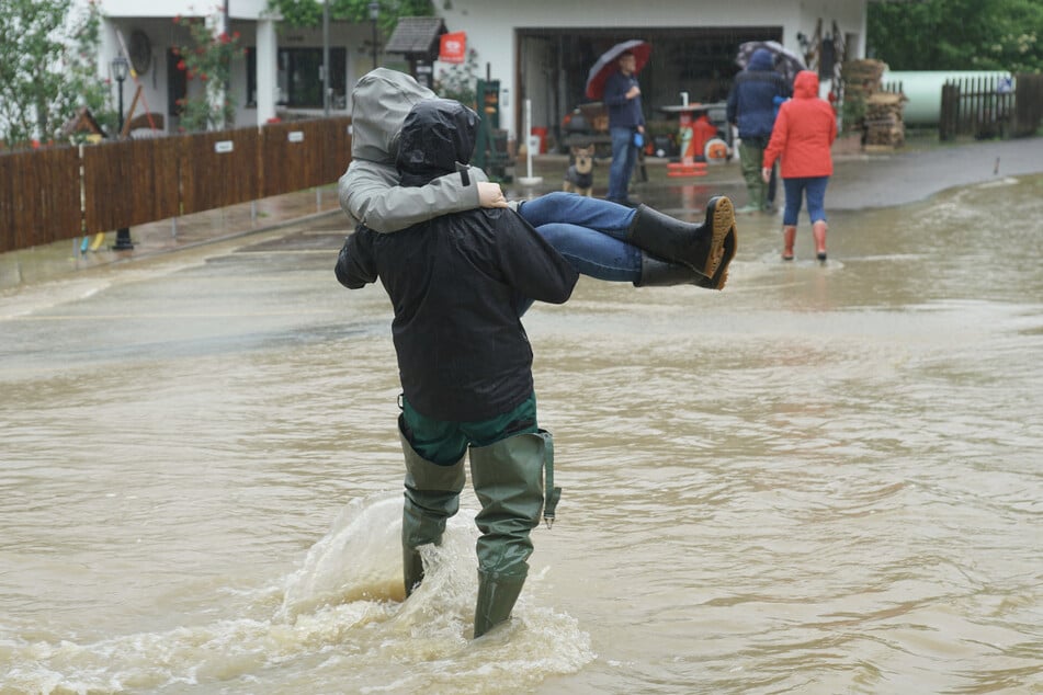 In Albershausen im Landkreis Göppingen stehen Straßen unter Wasser, Menschen werden durch die Fluten getragen.