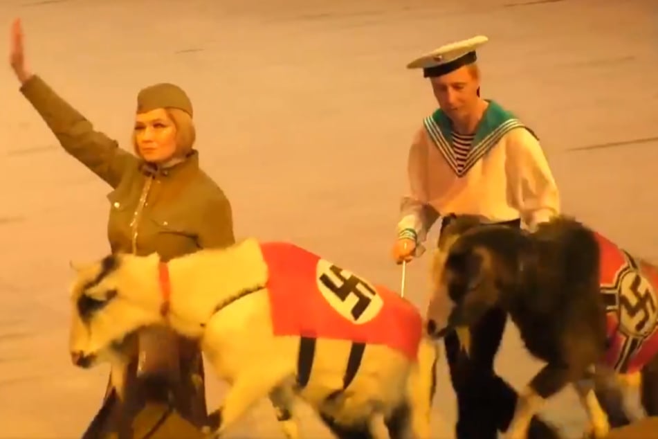Mit Hakenkreuzen bedeckte Ziegen werden durch die Manege geführt.