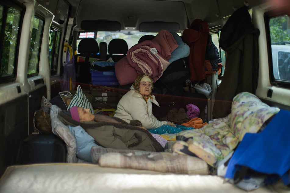 Zwei Frauen sitzen in der heftig umkämpften Stadt Bachmut im Osten der Ukraine in einem Lieferwagen.