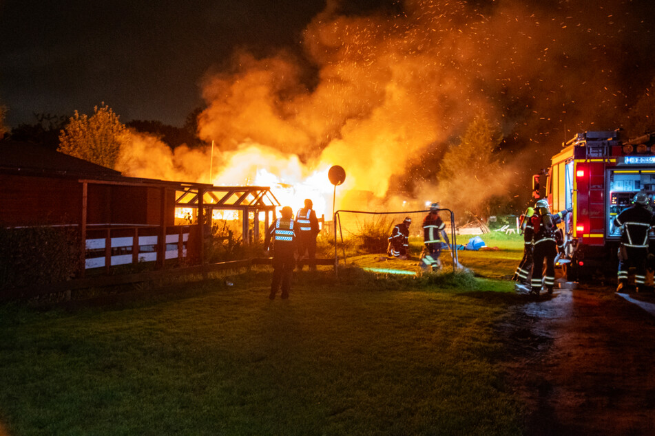 Die Feuerwehr kämpft gegen die Flammen, kann jedoch nicht verhindern, dass die Gartenlaube vollständig ausbrennt.