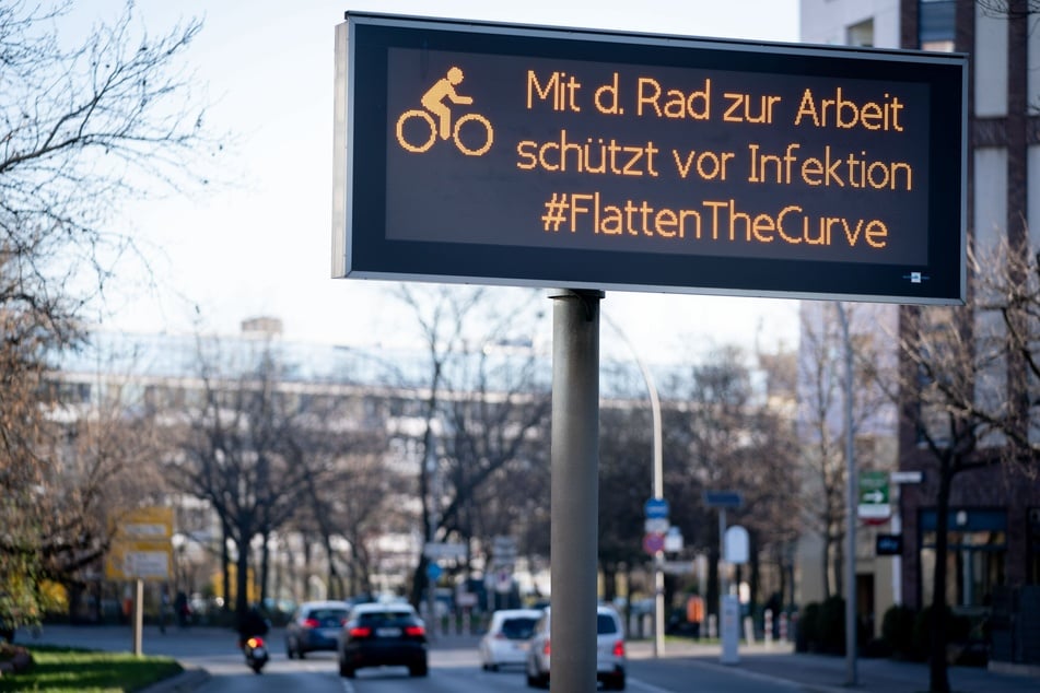 "Mit dem Rad zur Arbeit schützt vor Infektion #FlattenTheCurve" steht auf einem Hinweisschild an einer Straße in Berlin.