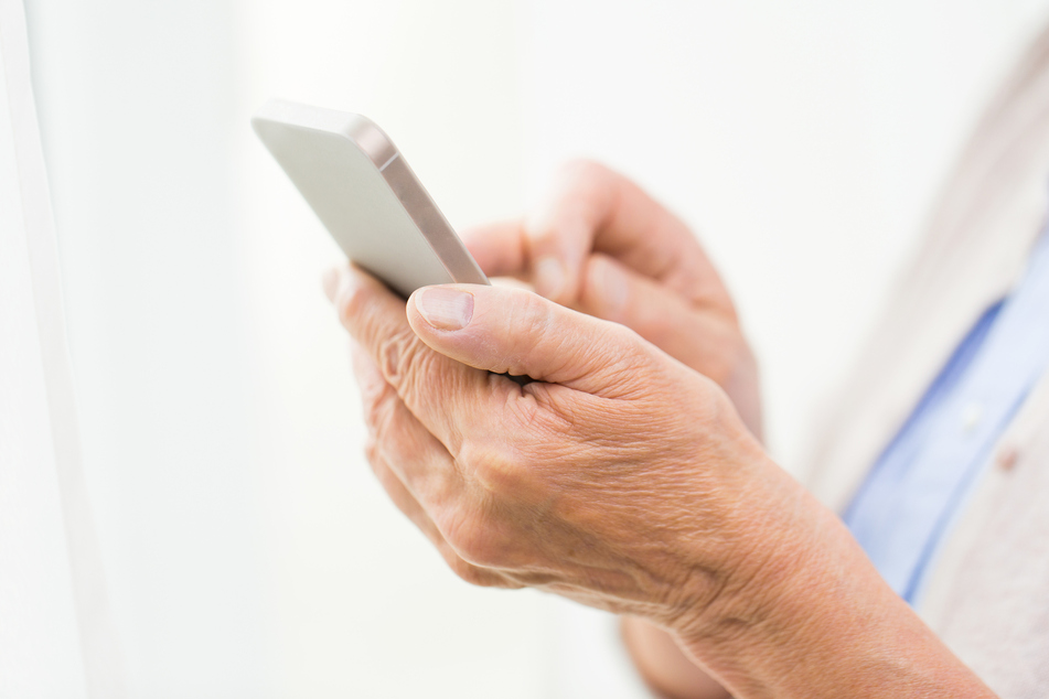 Eine ältere Dame hält ein Handy in der Hand. (Symbolbild)