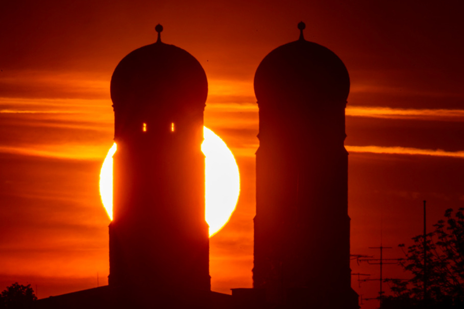 Die Sonne geht am frühen Morgen zwischen den Türme der Frauenkirche auf, die im Herzen der bayerischen Landeshauptstadt steht.