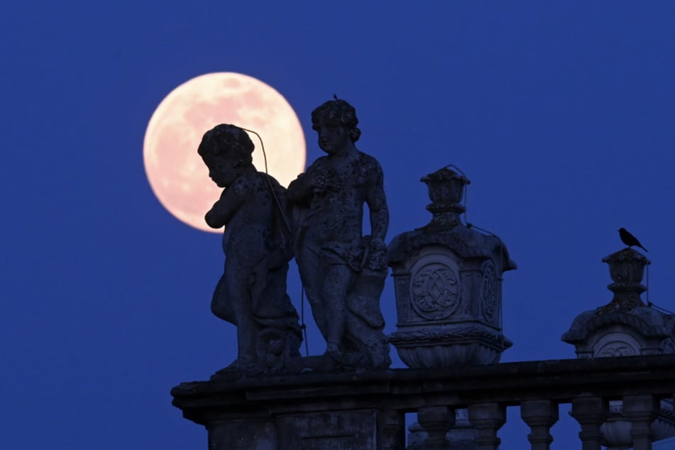 Der Mond hinter Statuen und Amphoren auf dem Dach der Orangerie in Kassel.