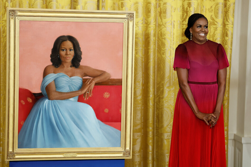 Former First Lady Michelle Obama poses next to her official White House portrait, painted by Sharon Sprung.