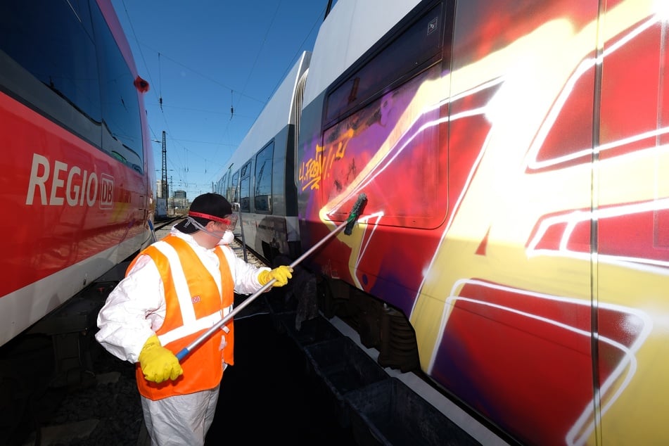 Ein Graffiti-Entferner arbeitet am Leipziger Hauptbahnhof an einem besprühten S-Bahnwagen.