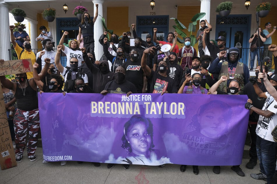 Demonstrators pose for a photo in front of a local restaurant on a third day of protest over the lack of criminal charges in the police killing of Breonna Taylor and the result of a grand jury inquiry, in Louisville, Kentucky, on September 25, 2020.