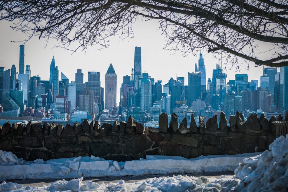 Snow covers sidewalks as the New York skyline is seen in the background from Weehawken, New Jersey, on February 1, 2026.