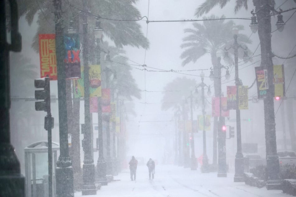 People make their way down a snowy Canal Street in New Orleans, Louisiana, on January 21, 2025.