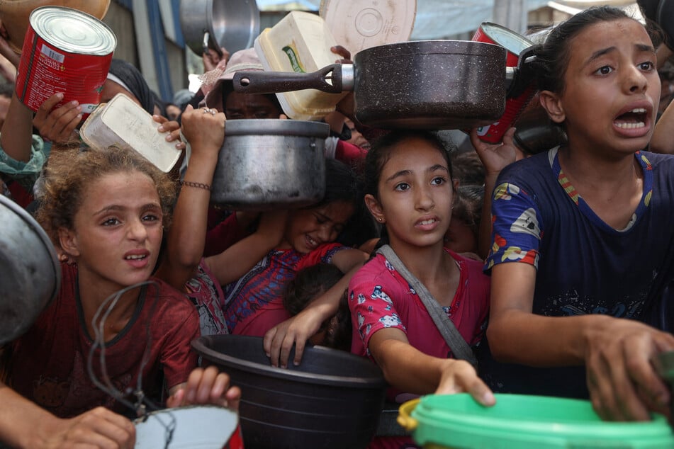 Palestinian children gather to receive cooked meals from a food distribution center in the Nuseirat refugee camp in the central Gaza Strip on August 18, 2025.