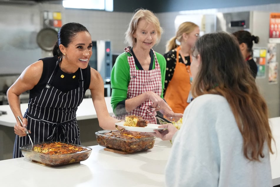 Meghan (l.), the Duchess of Sussex, serves lunch to a resident alongside staff of the McAuley Community Services for Women, a homeless and family violence shelter, in Melbourne on Tuesday.