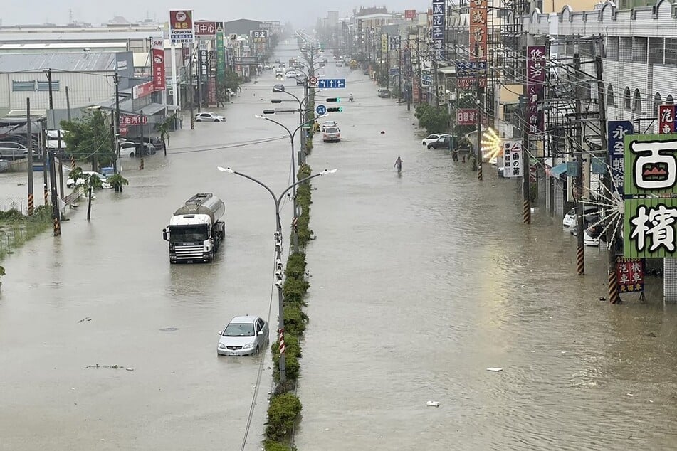 People and vehicles wade through the water along a street that was flooded by Typhoon Gaemi in Kaohsiung, Taiwan, on July 25, 2024.