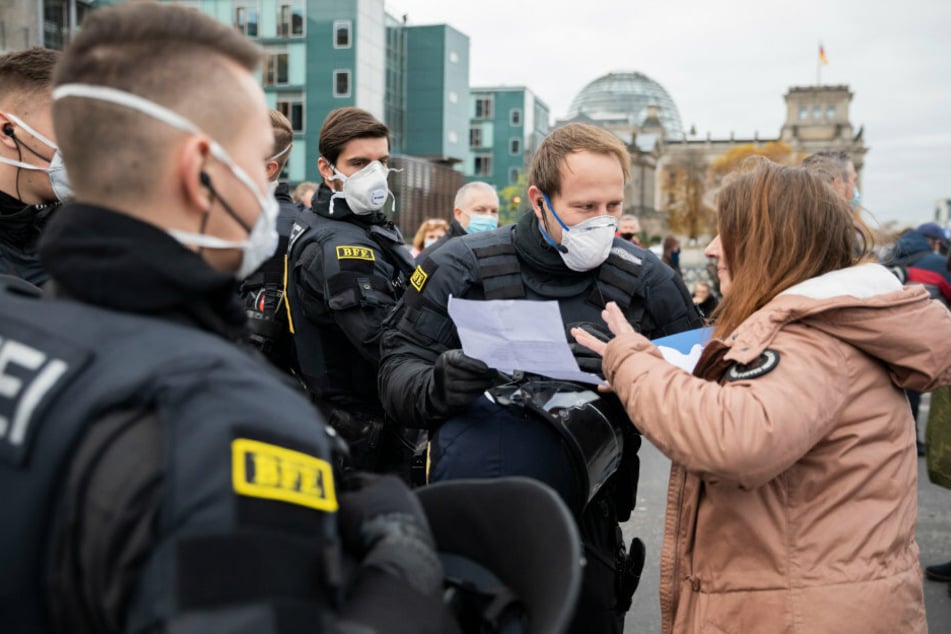 Polizisten kontrollieren bei einer Demonstration das Attest einer Frau zur Befreiung von der Maskenpflicht. Wegen falscher Corona-Atteste ermittelt das Landeskriminalamt in der Hauptstadt in dutzenden Fällen gegen Ärzte.