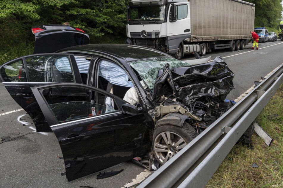 Ein zestörter PKW steht an einer Leitplanke, vor einem beschädigten Lkw.
