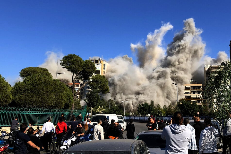 Menschen in Beirut (Libanon) beobachten, wie Rauch aus einem Gebäude aufsteigt.