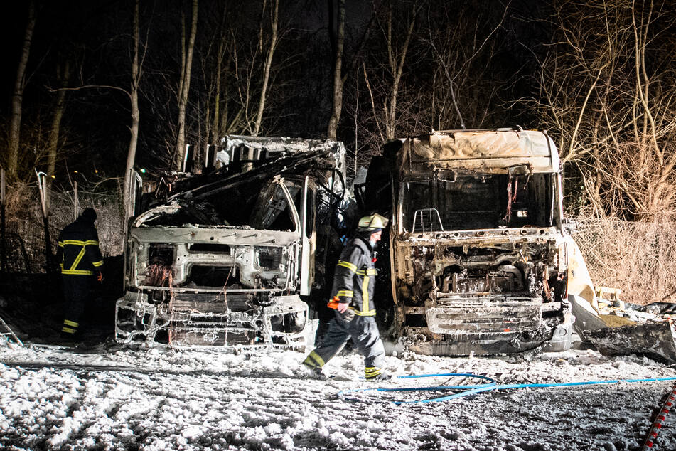 Ein Feuerwehrmann geht an den Wracks der beiden ausgebrannter Lastwagen vorbei.