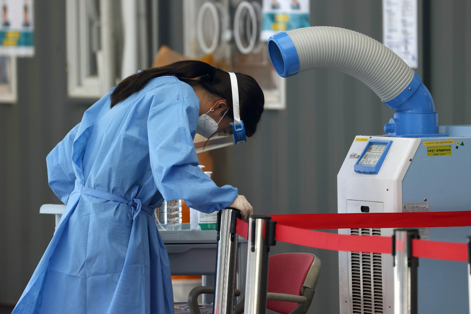 Seoul: Eine medizinische Mitarbeiterin einer Corona-Teststation steht vor einem Luftkühler inmitten sengender Hitze.