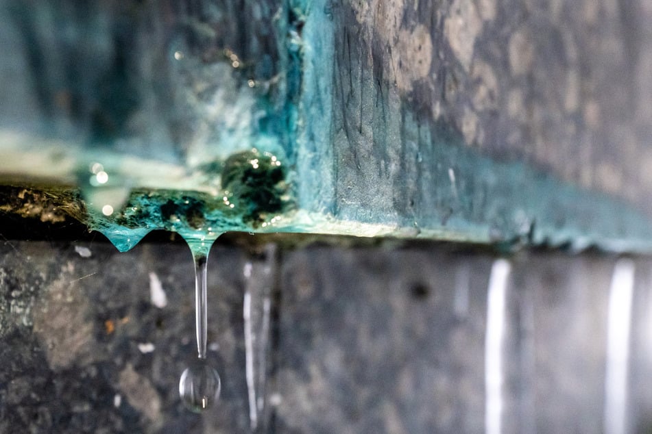 Tropfen und Eiszapfen zeigen, wo am Sockel des Denkmals Wasser austritt.