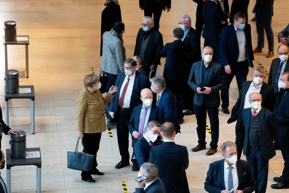 Bundeskanzlerin Angela Merkel (66, CDU, l) unterhält sich am Rande der 215. Sitzung des Bundestags mit Abgeordneten vor einer namentlichen Abstimmung. Themen sind unter anderen die epidemische Lage von nationaler Tragweite und die Auswirkungen des Lockdowns für die Wirtschaft.