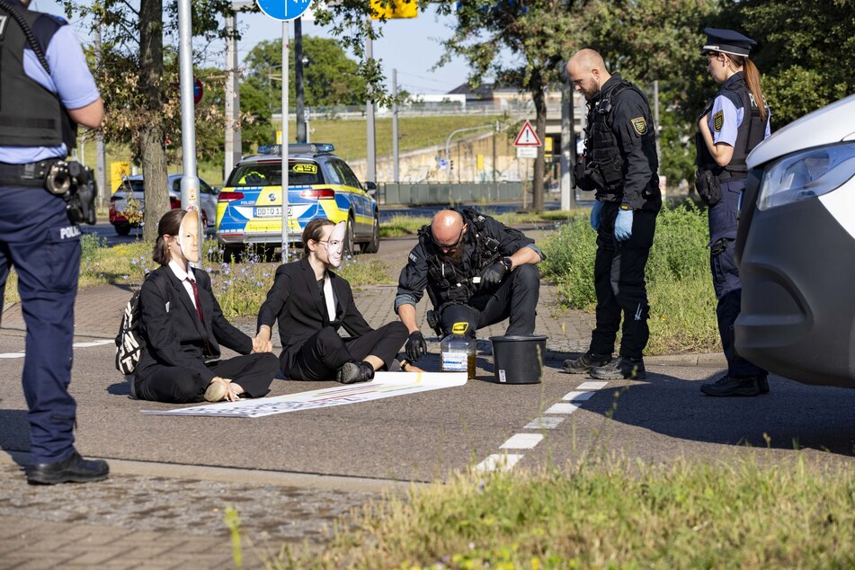 Einsatzkräfte der Polizei lösten die angeklebten Aktivisten von der Straße.