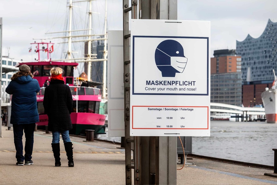Ein Hinweisschild mit der Aufschrift "Maskenpflicht" hängt an den Landungsbrücken.