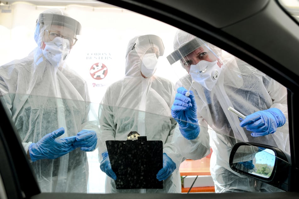 Mitarbeiter vom Gesundheitsamt halten ein Abstrichstäbchen in ein Autofenster in der ambulanten Corona-Test-Einrichtung. (Archivbild)