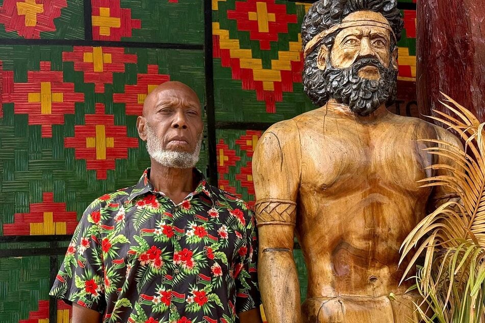 Head chief of the volcanic island of Ambrym, George Bumseng, stands next to a wooden statue in the Vanuatu capital of Port Vila on July 24, 2025.