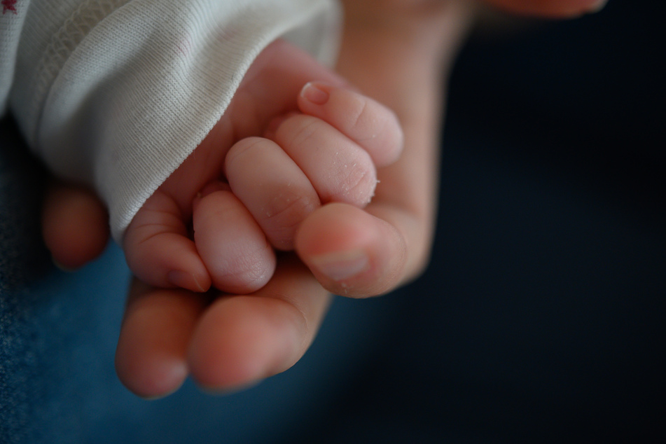 Baden-Württemberg, Stuttgart: Die Hand eines zwei Wochen altes Neugeborenen liegt in der Hand seiner Mutter.