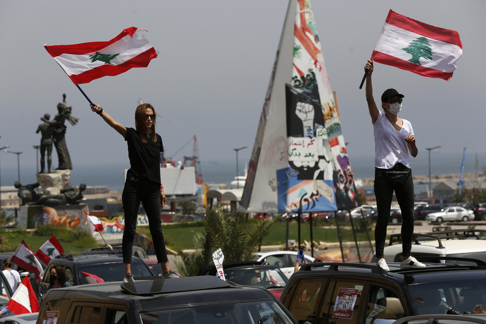 Regierungskritische Demonstrantinnen stehen auf ihren Autos und schwenken libanesische Flaggen.