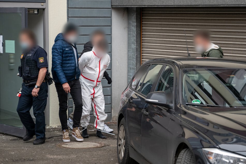 Polizisten bringen einen der Tatverdächtigen (im weißen Overall) nach dem Haftprüfungstermin am Landgericht Kaiserslautern aus dem Justizgebäude.