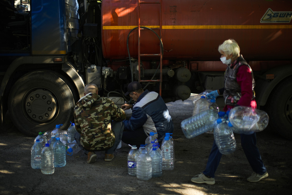 Arbeiter füllen in einer ukrainischen Unterkunft für Verletzte und Obdachlose Plastikflaschen mit Wasser auf.
